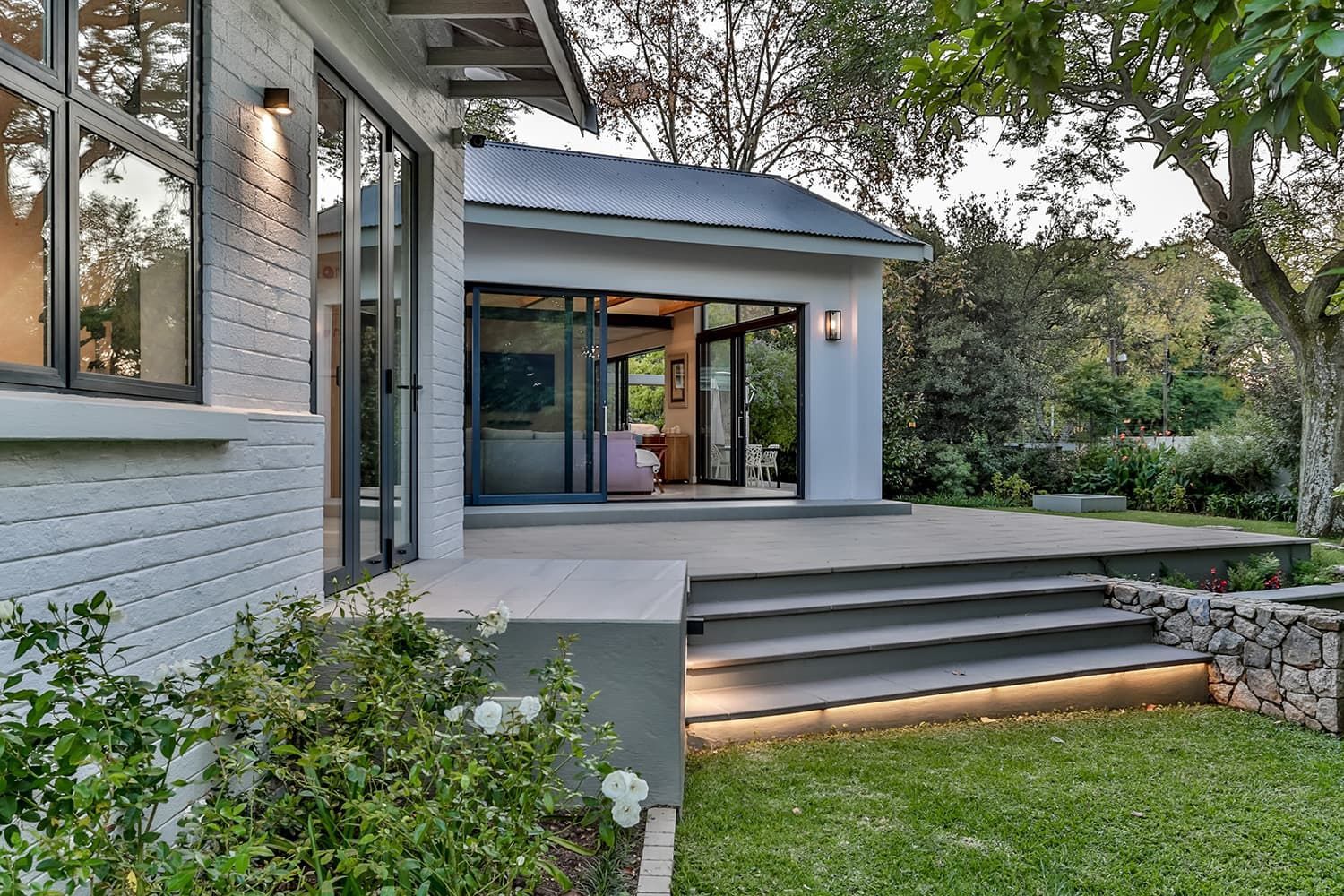 A white house with a sliding glass door and stairs leading to it.