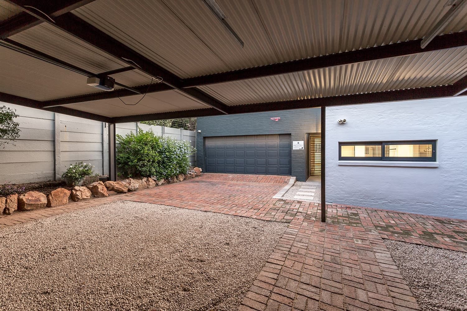 A brick driveway with a carport in front of a house