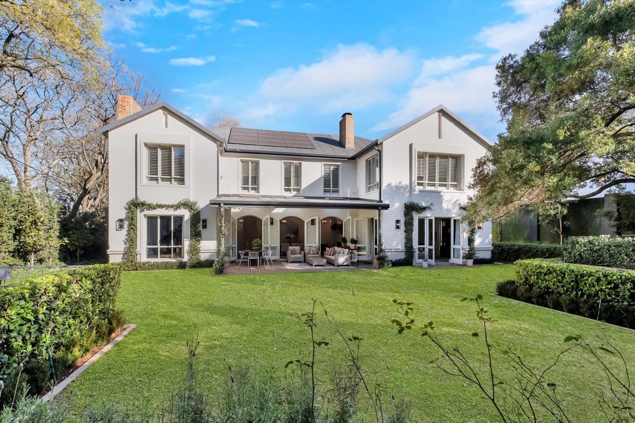 A patio with a couch , chairs and a table with a view of a lush green field.