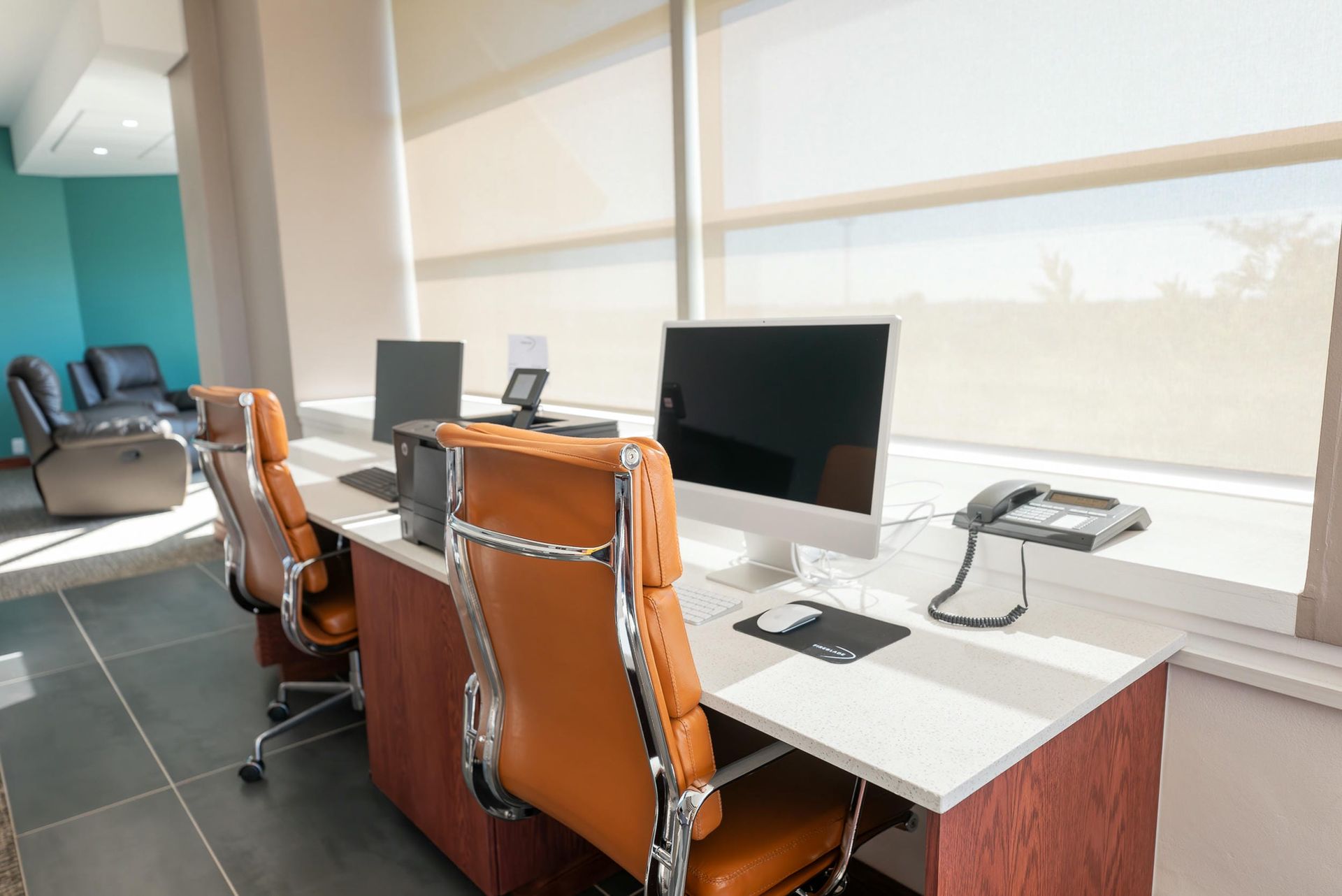 A row of desks with computers and chairs in an office.