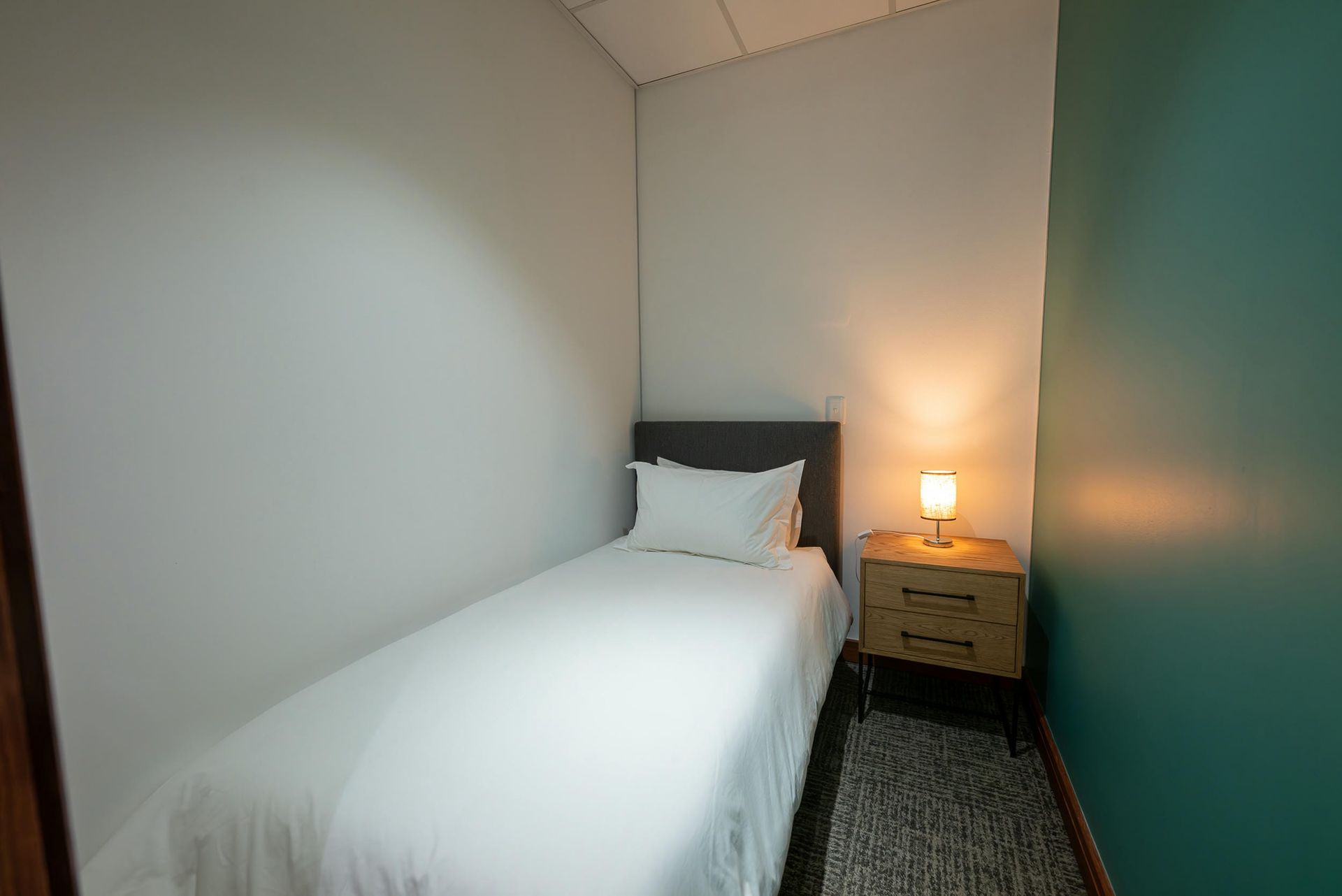 A small bedroom with a single bed and a nightstand.