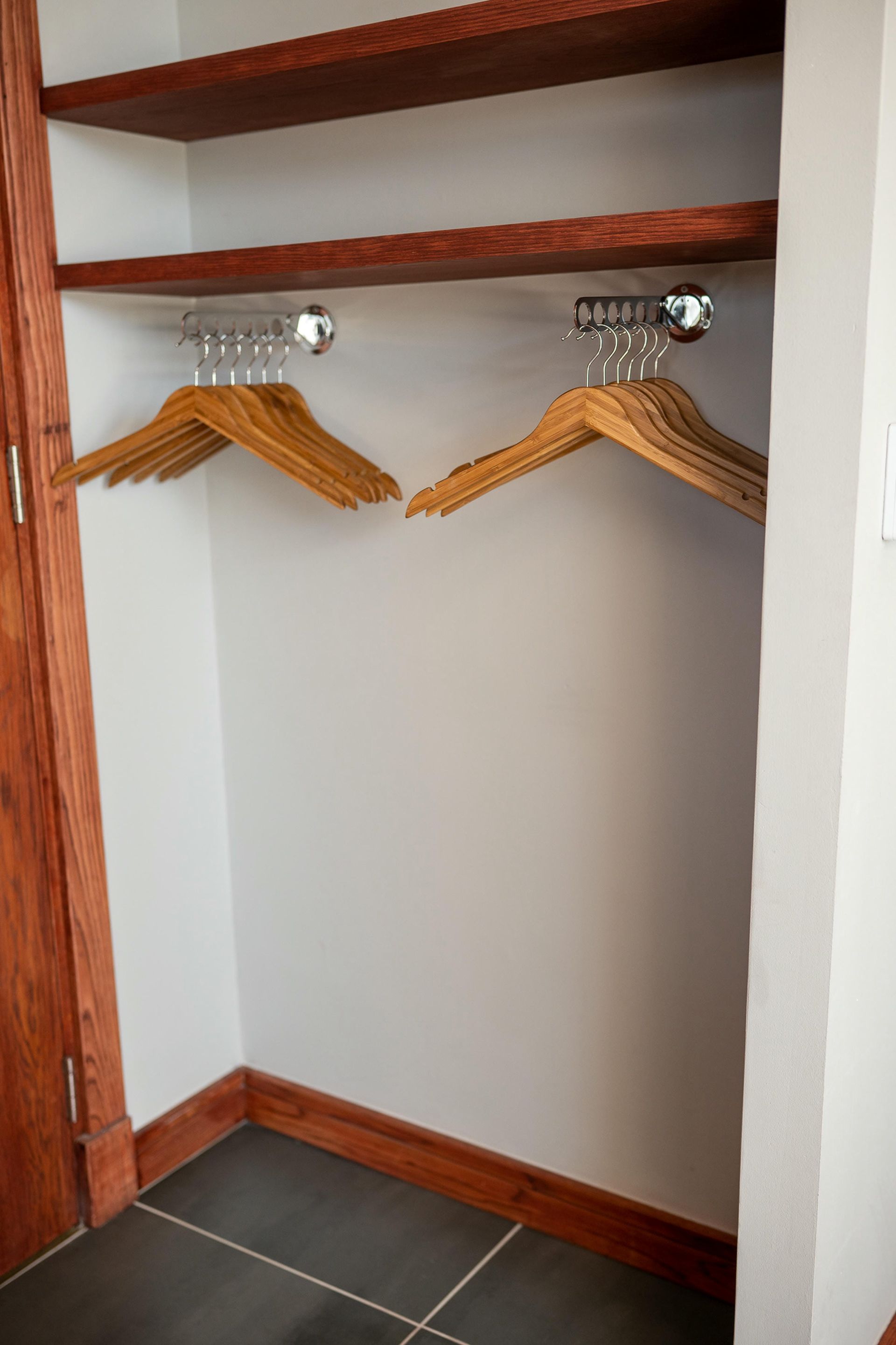A closet with two wooden hangers hanging on the wall.