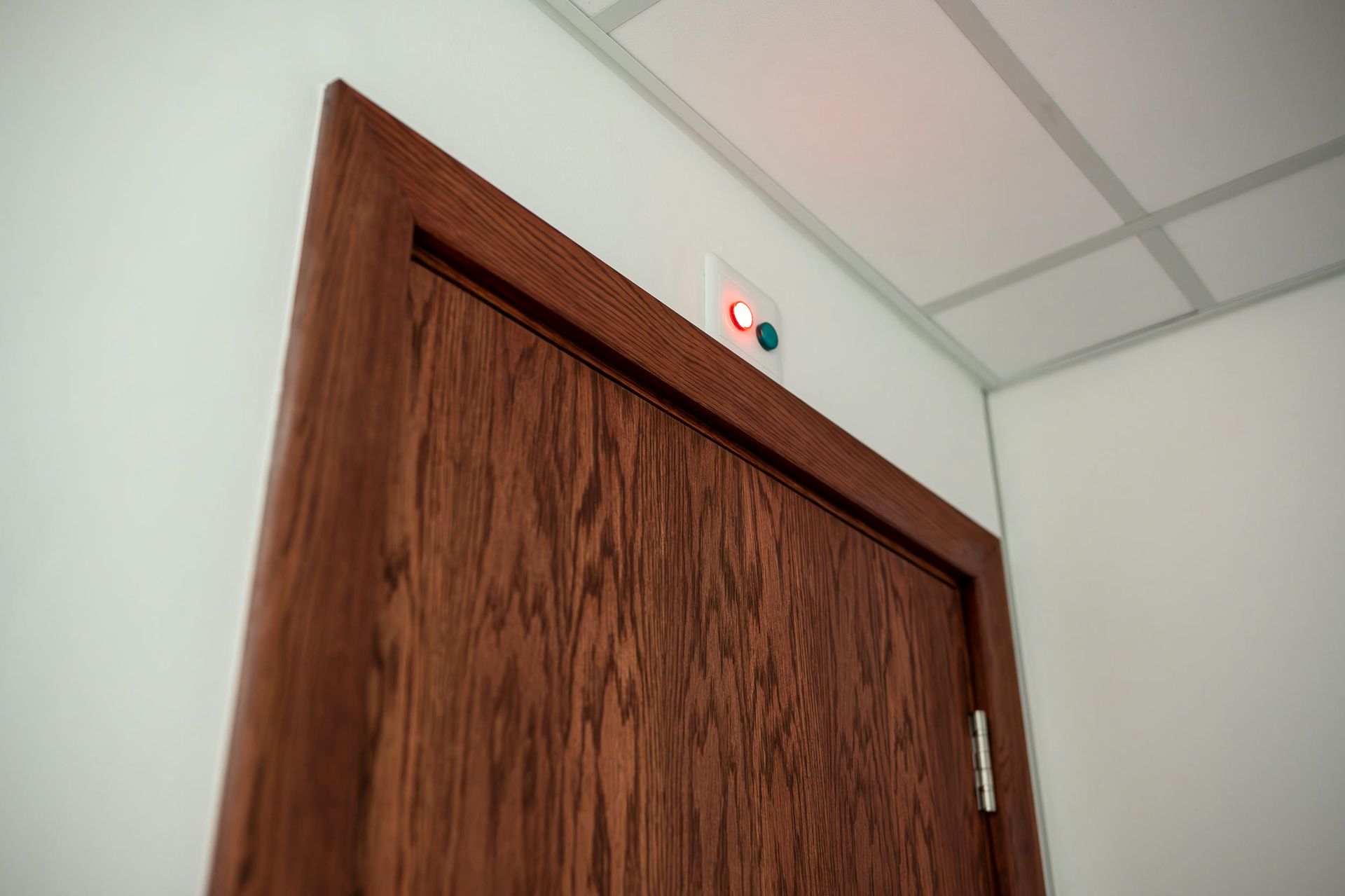A close up of a wooden door with a red light on it.