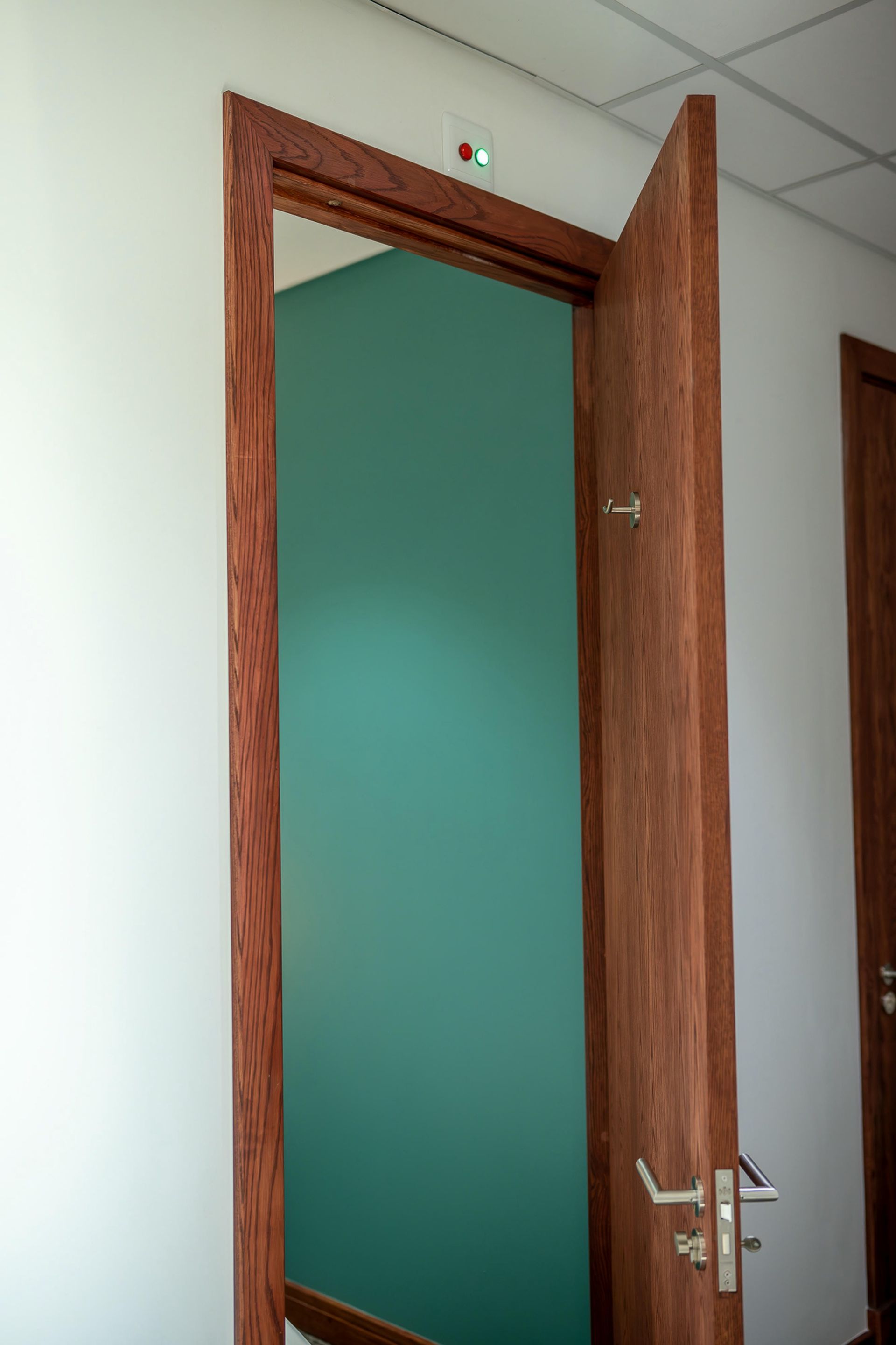 A wooden door is open to a room with a green wall