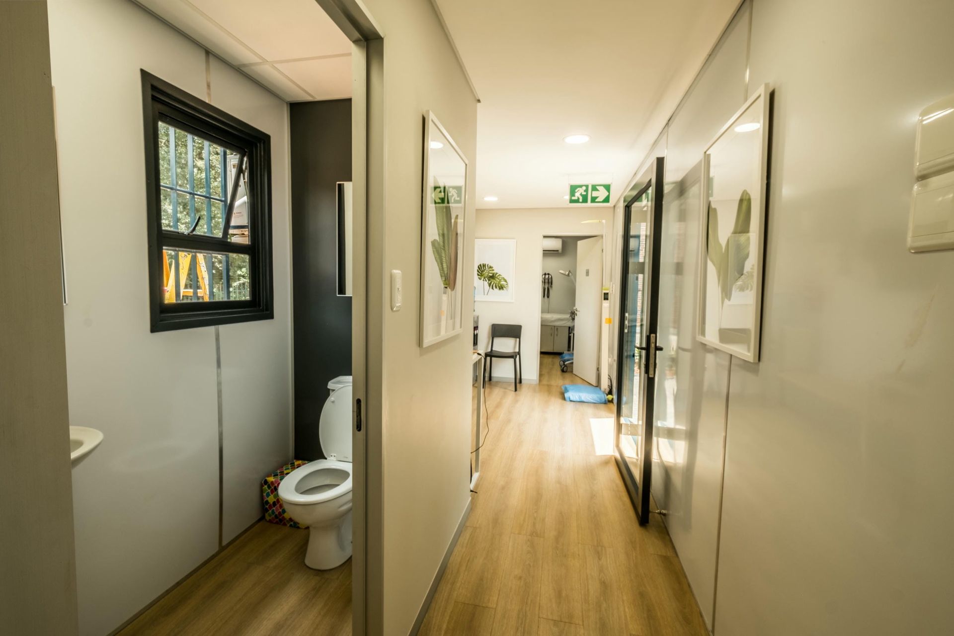 A long hallway with a toilet , sink and window.