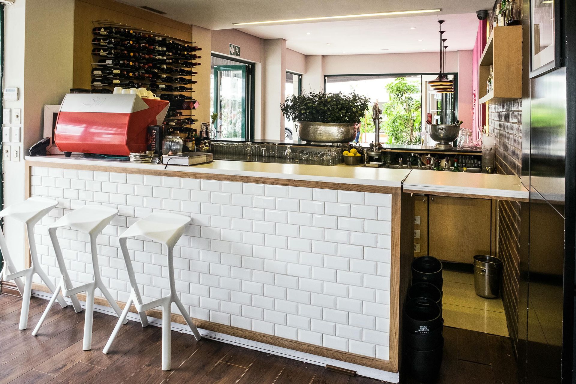 A bar with white stools and a red espresso machine