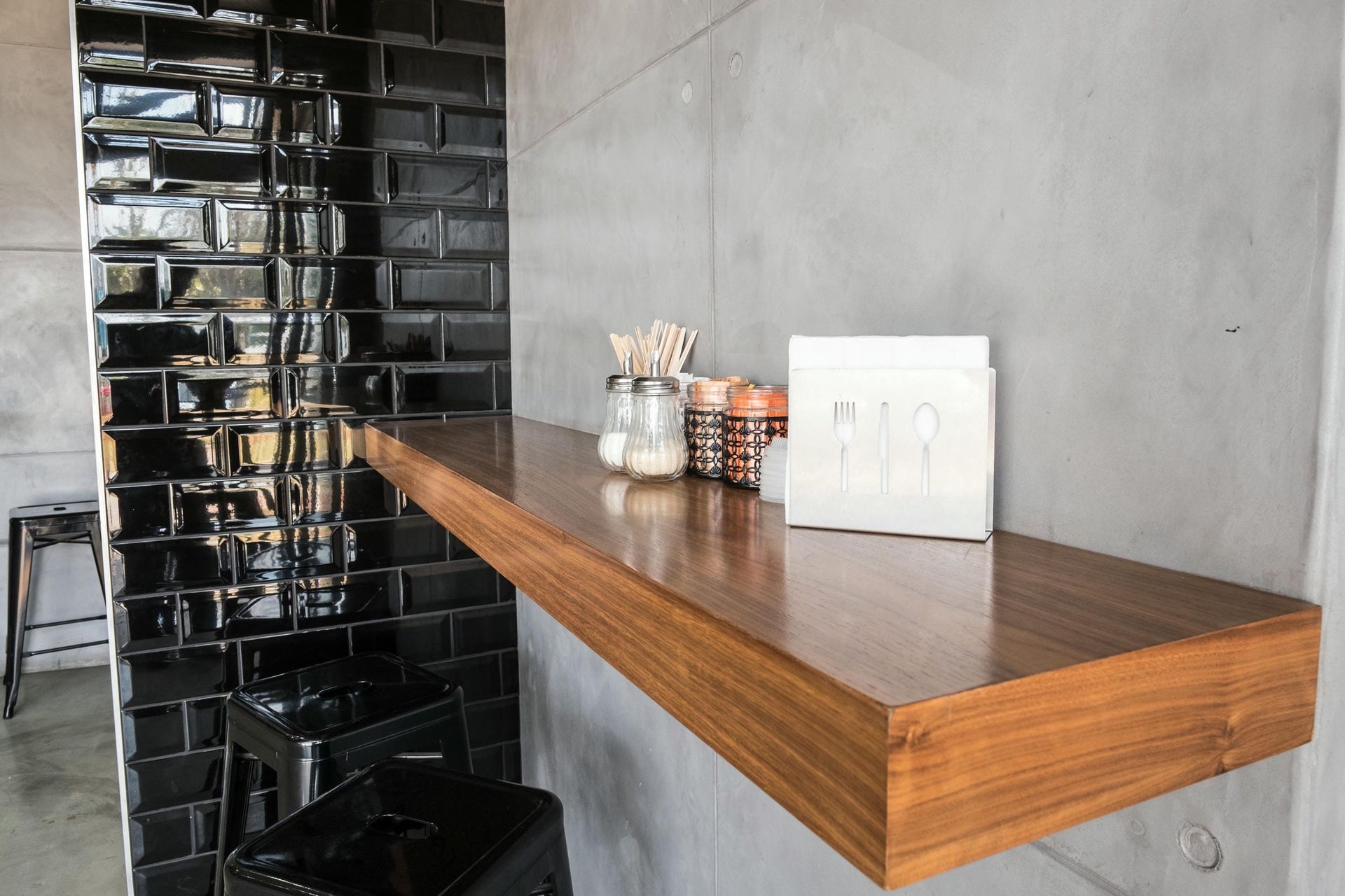 A wooden shelf with a white box on it in a room with black tiles.