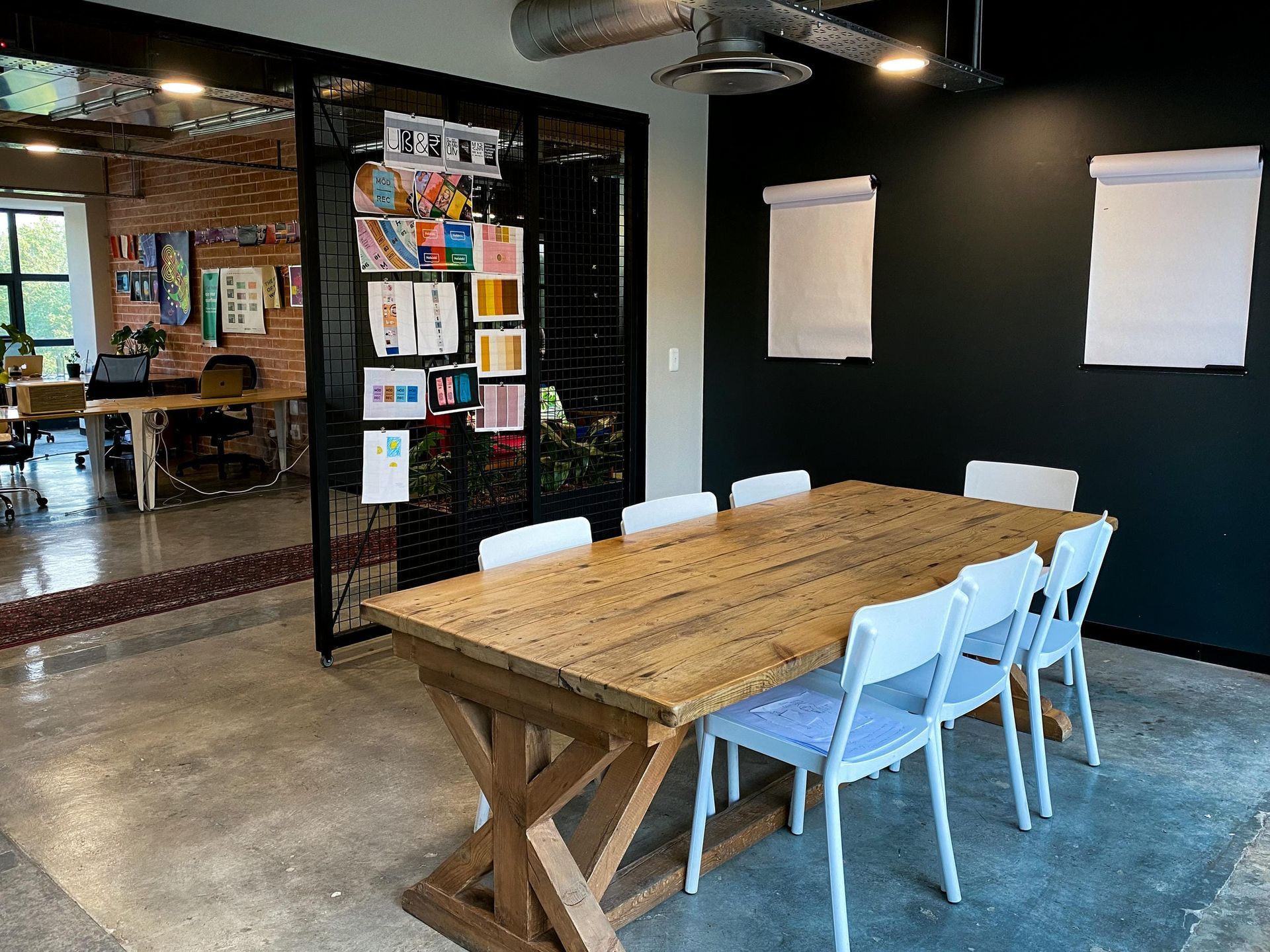 A conference room with a long wooden table and white chairs.