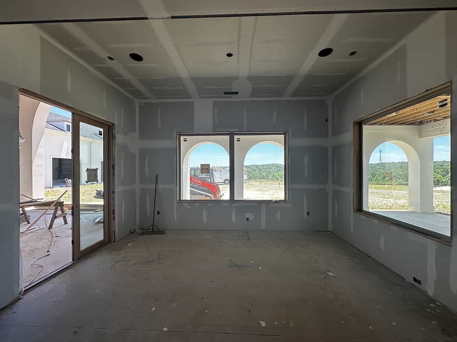 An empty room with a lot of windows and drywall on the walls.