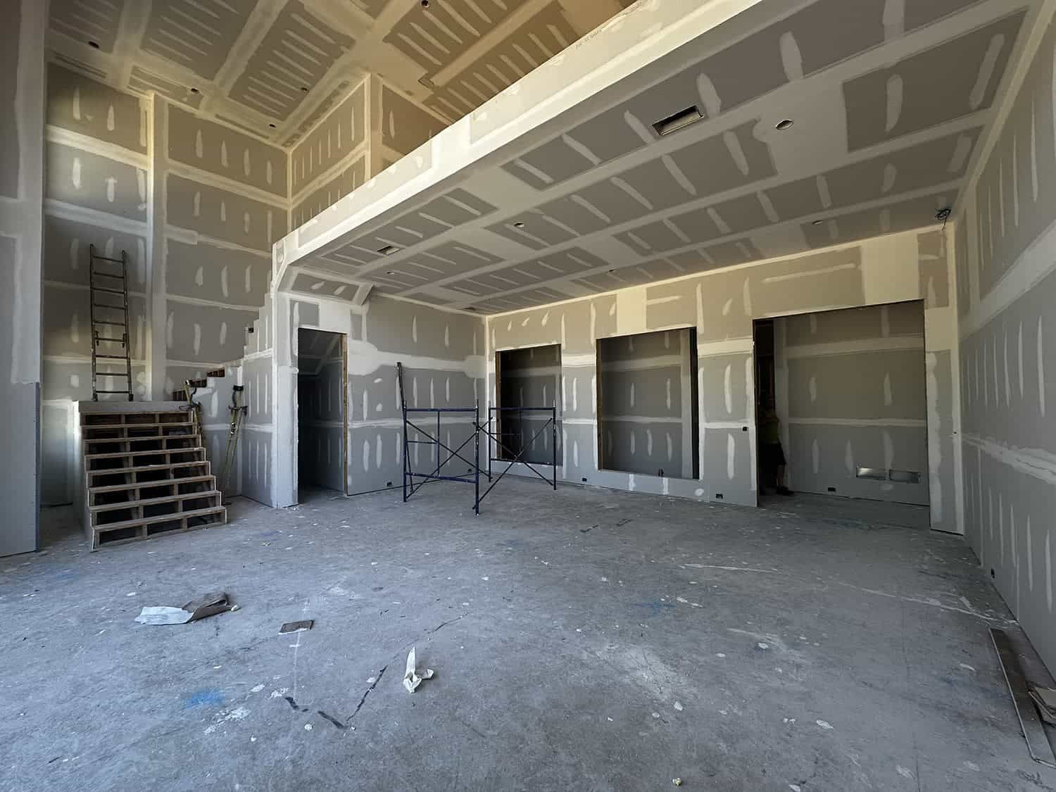 An empty room with drywall walls and a staircase
