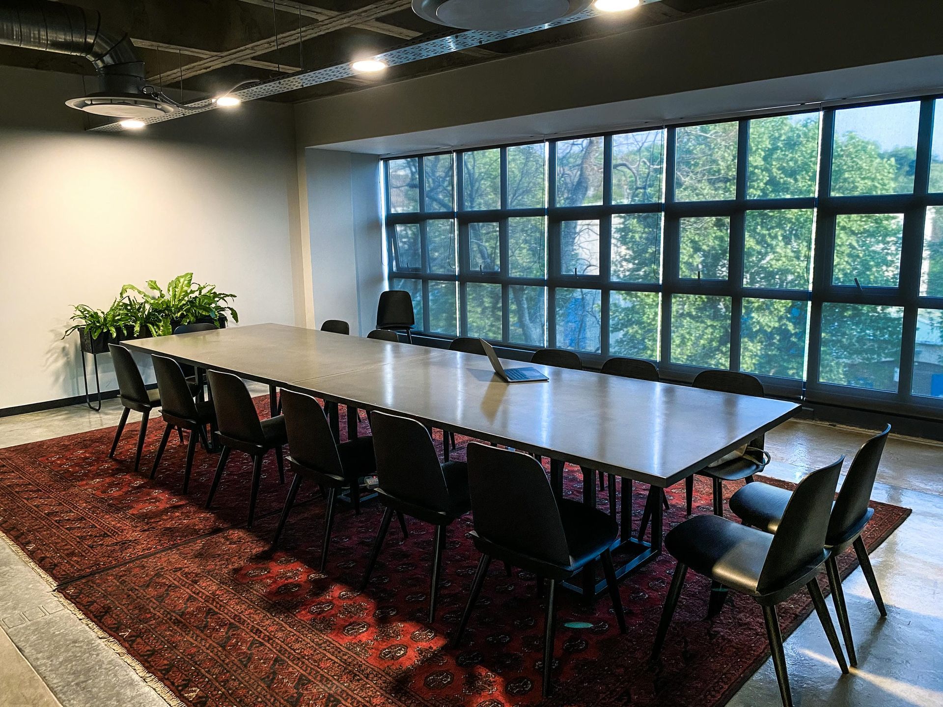 A conference room with a long table and chairs in front of a large window.