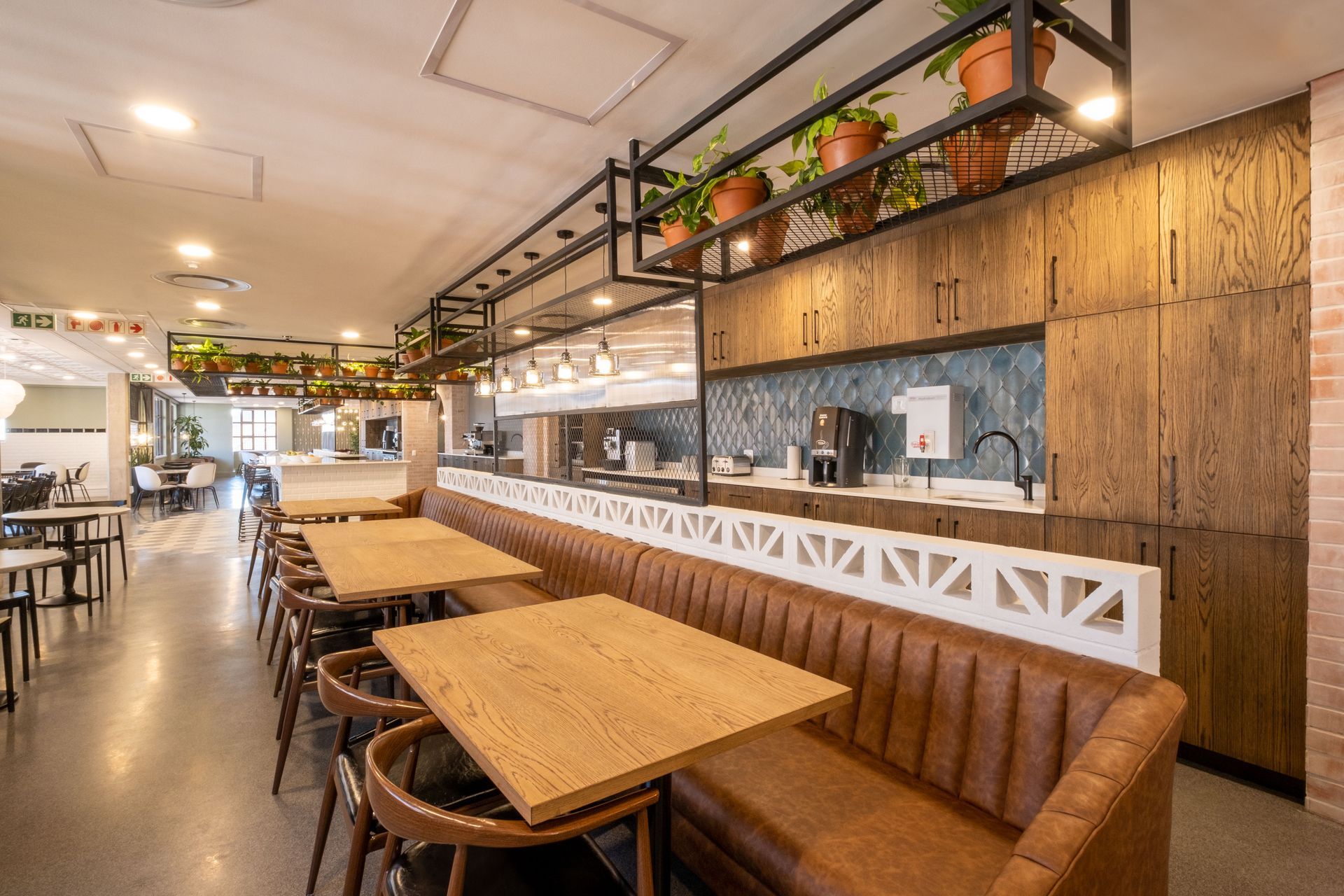 A restaurant with tables and chairs and a long bench.