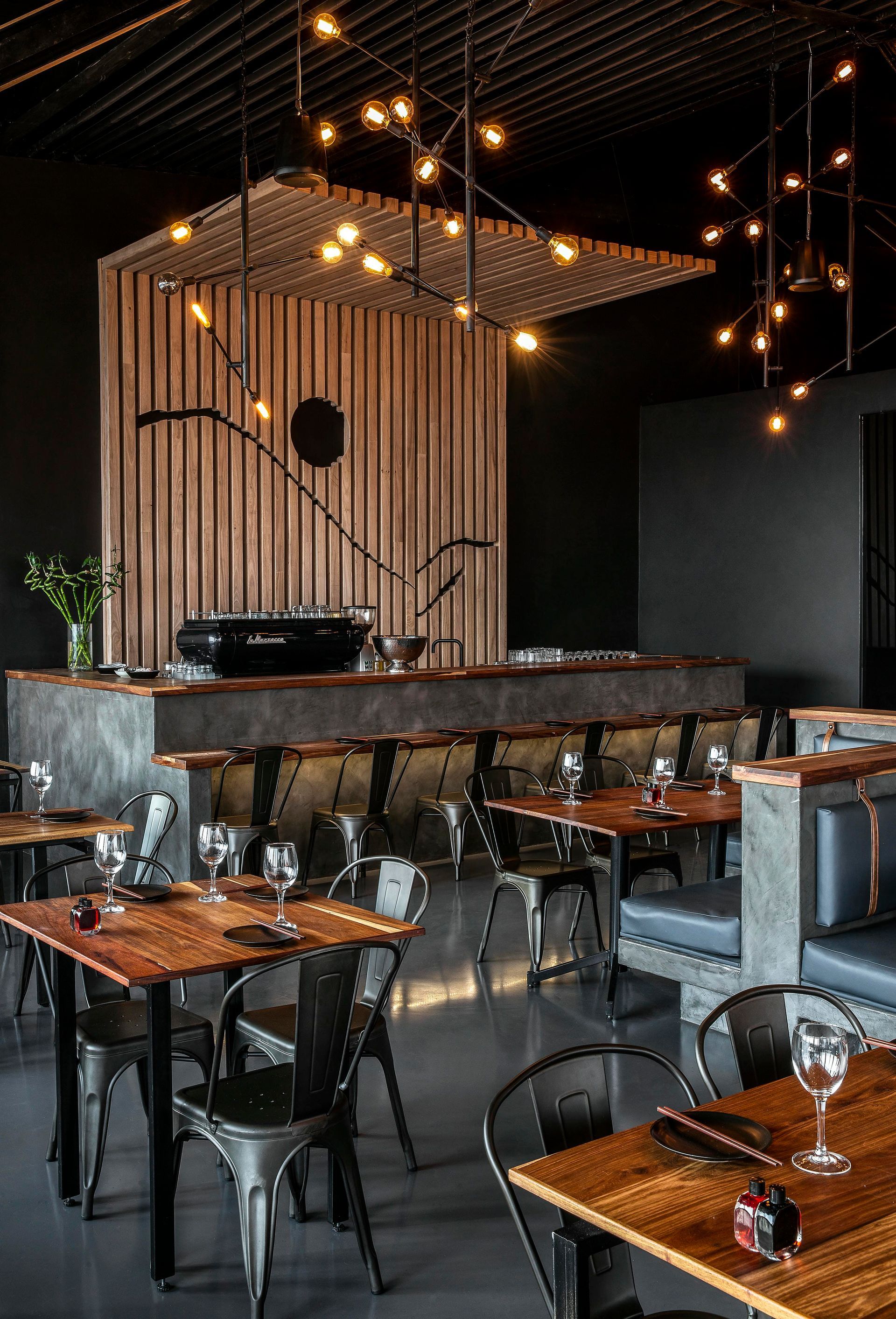 A restaurant with wooden tables and chairs in a dark room.