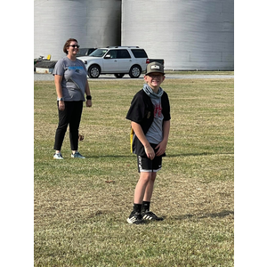 A woman and a boy are standing in a field.