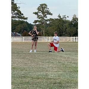 A man is kneeling down in front of a woman in a field.