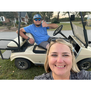 A man and a woman are sitting in a golf cart.