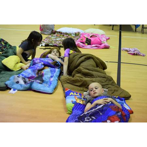 A group of children are sleeping in sleeping bags on the floor