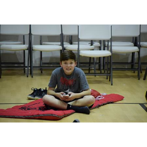 A young boy is sitting on the floor playing a video game.