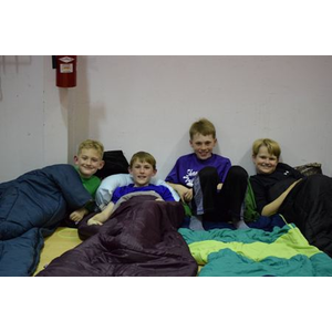 A group of young boys are laying in sleeping bags