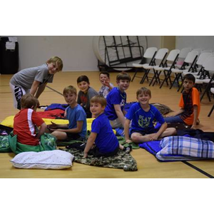 A group of young boys are sitting on the floor with blankets and pillows