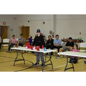 A boy is standing in front of a table with red cups on it