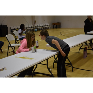 A boy and a girl are looking at something on a table