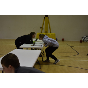 Two people are squatting on a table in a gym