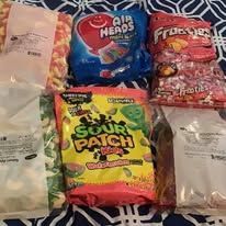 Assortment of candy: Sour Patch Kids, Airheads, and more, arranged on a patterned fabric.