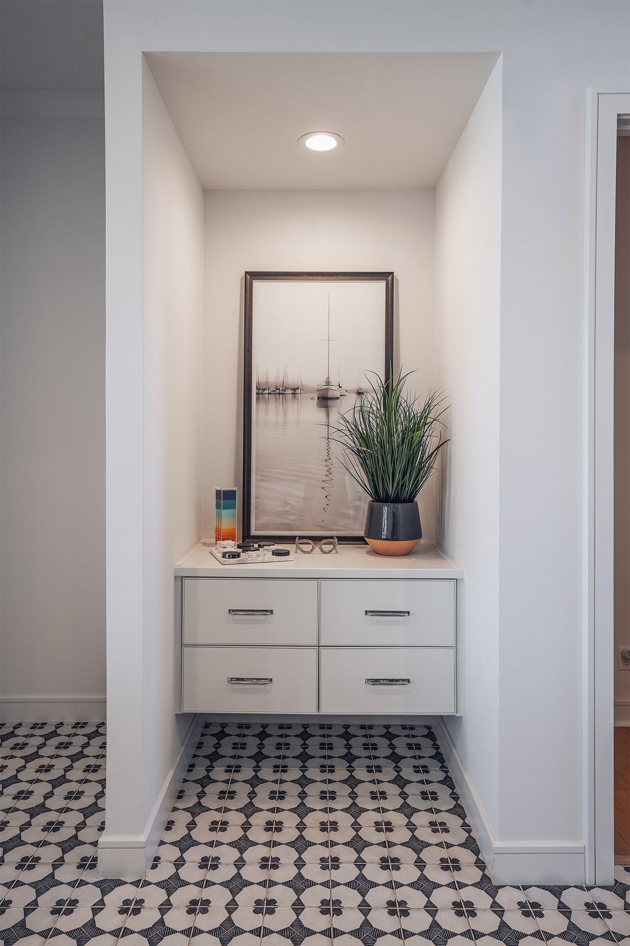 A hallway with a picture on the wall and a plant on the floor.