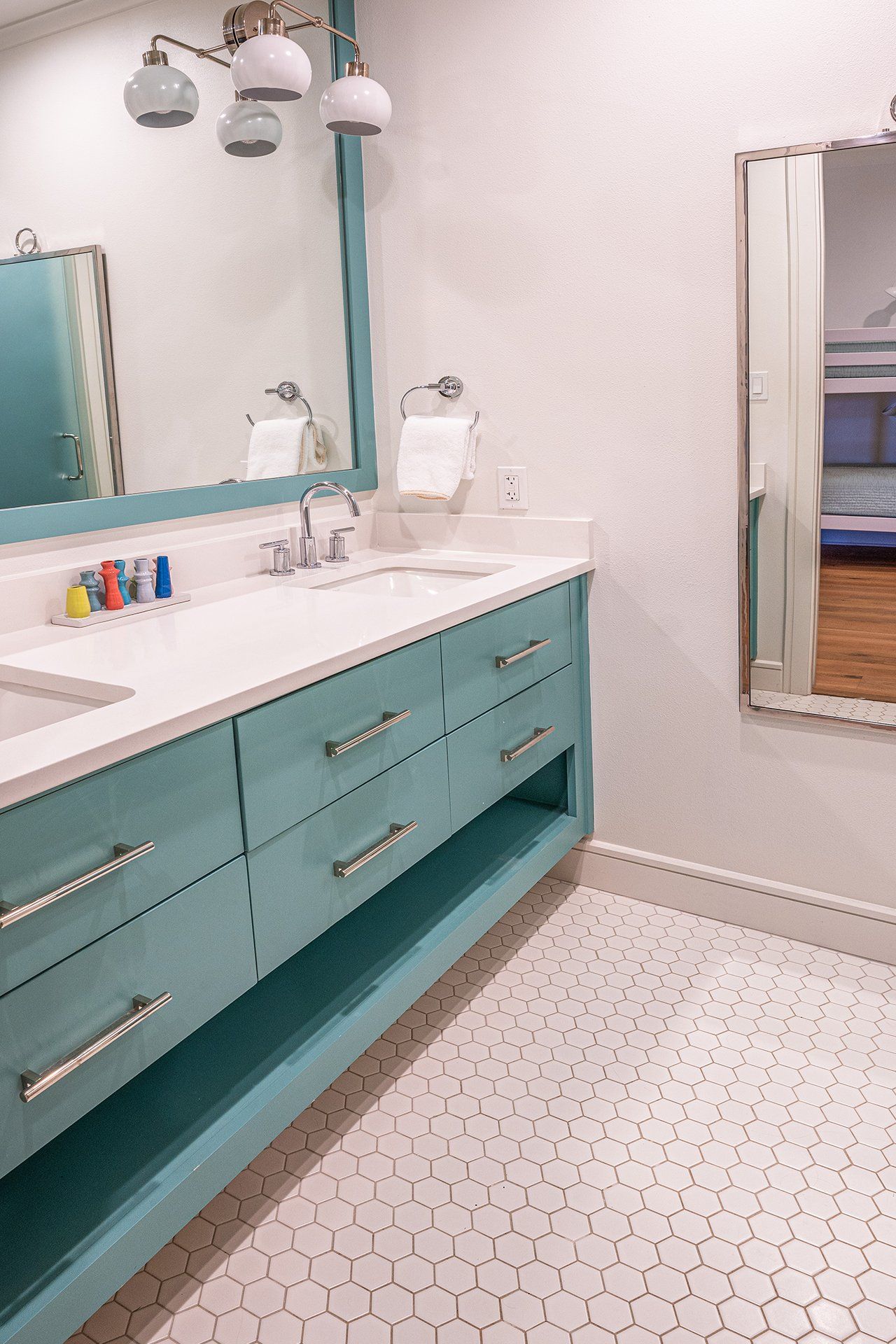 A bathroom with two sinks , a mirror , and blue cabinets.
