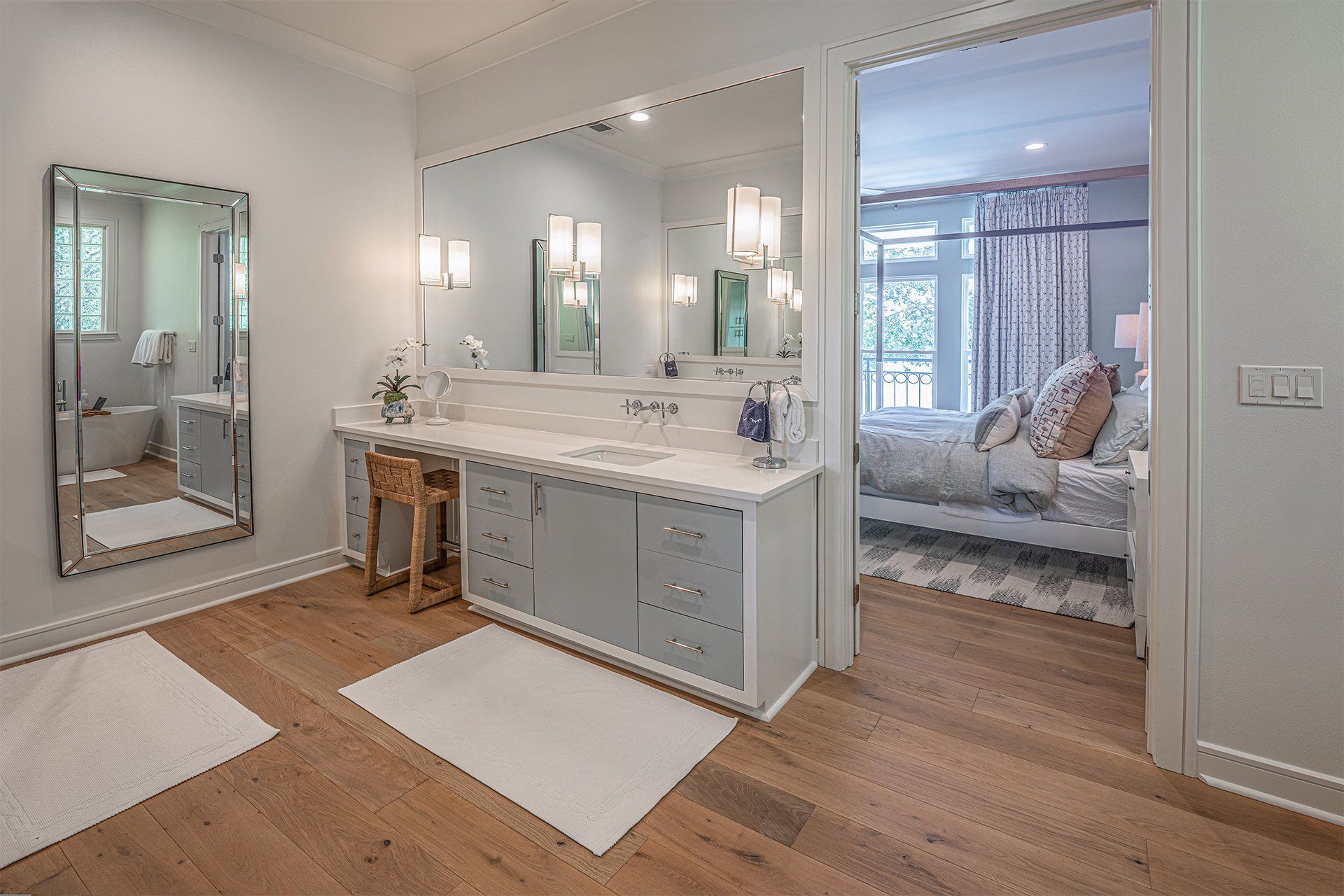 A bathroom with two sinks , two mirrors , and hardwood floors.