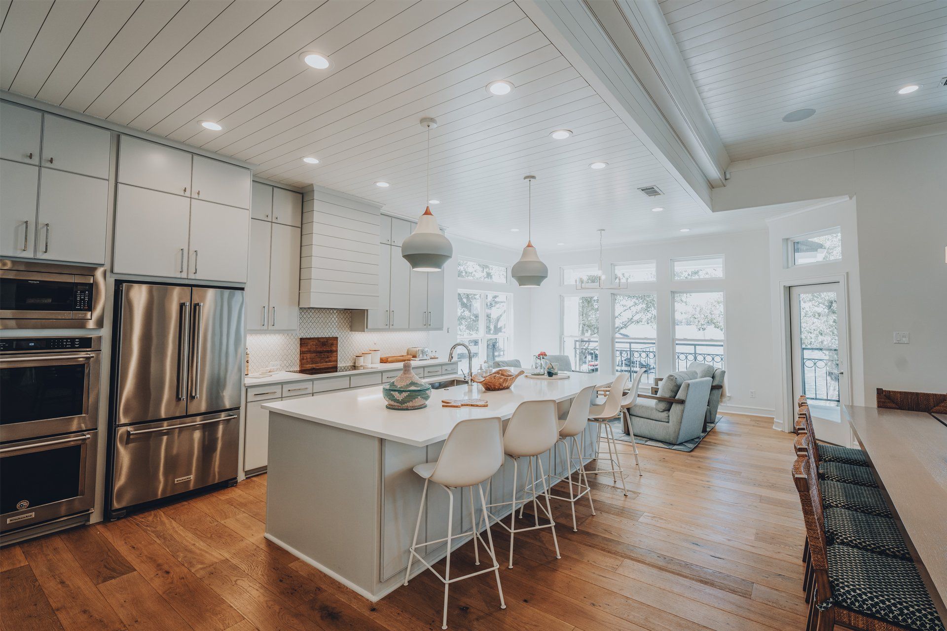 A kitchen with white cabinets , stainless steel appliances , a large island , and hardwood floors.