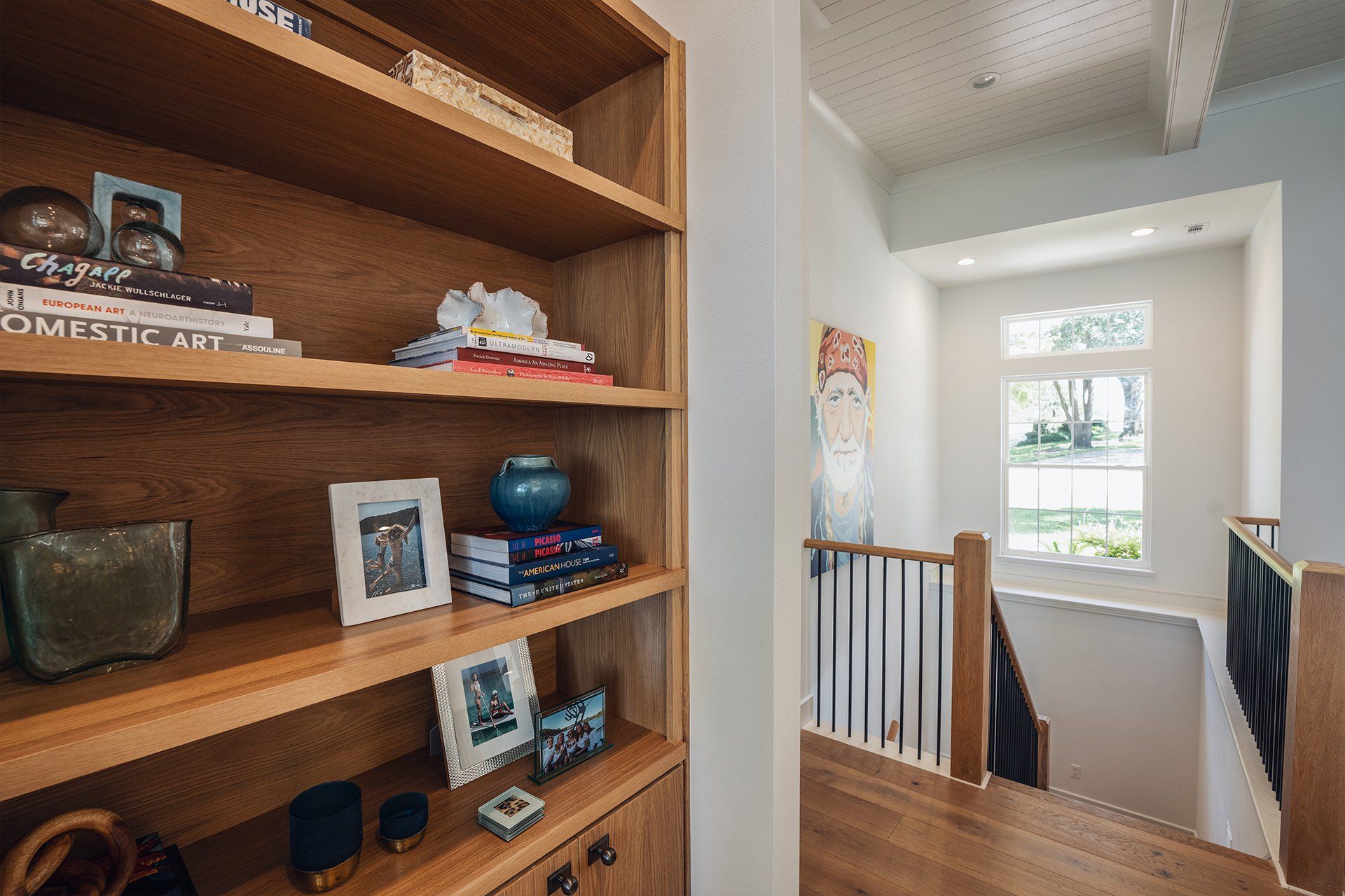 A bookshelf with books and pictures on it next to a staircase.