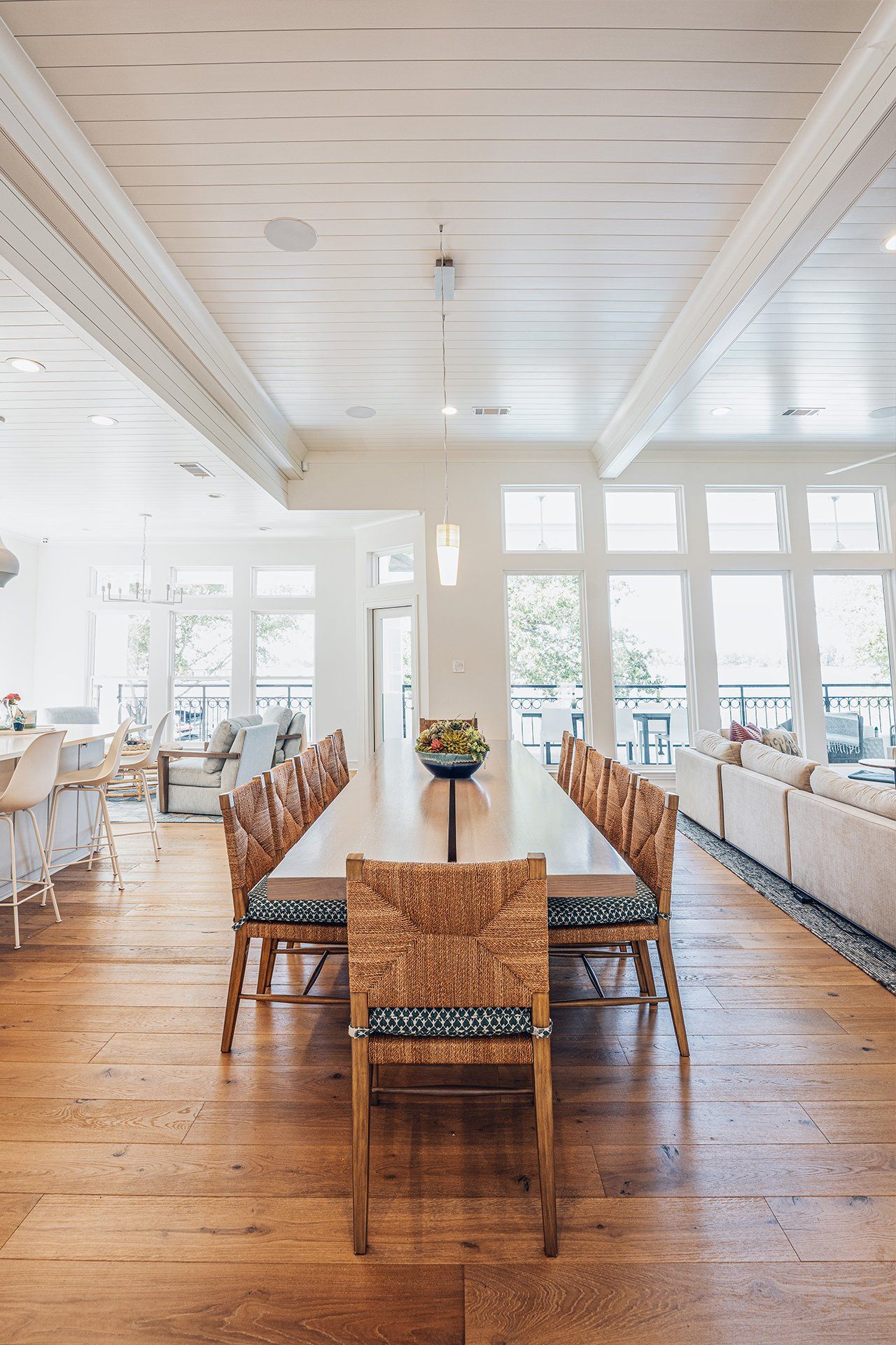 There is a long dining table with wicker chairs in the middle of the room.