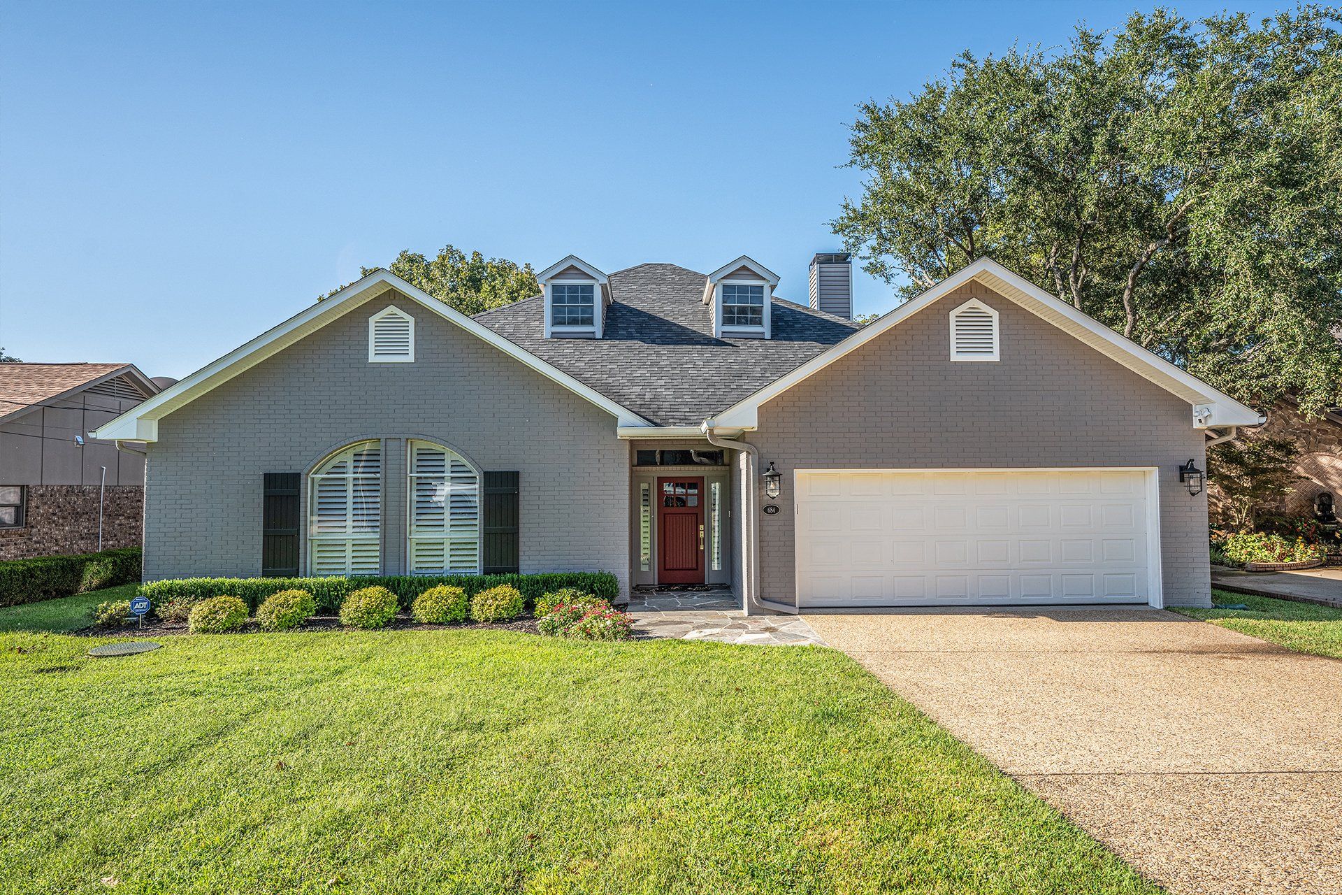 A large house with a white garage door and a large lawn in front of it.