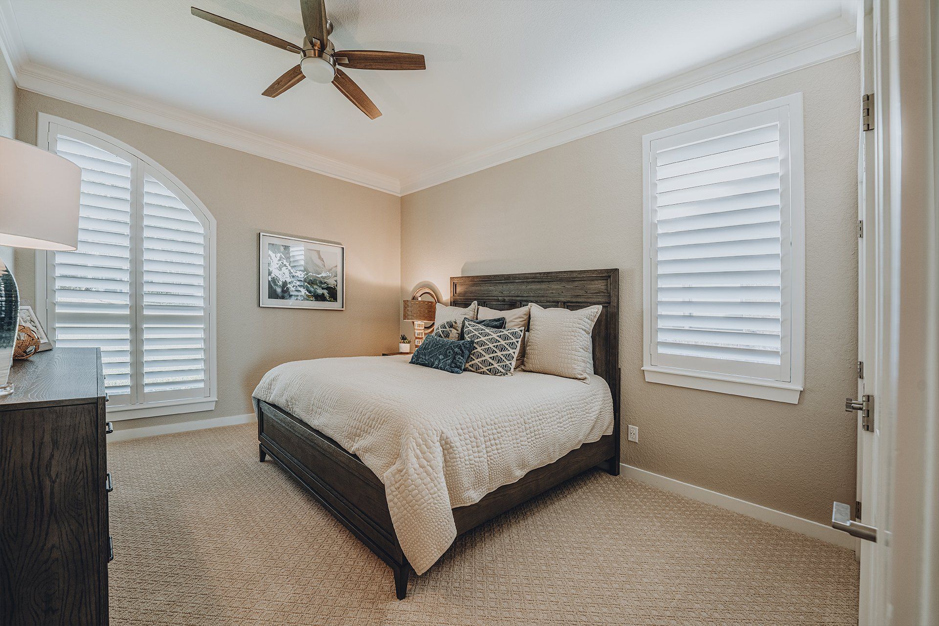 A bedroom with a bed , dresser , and ceiling fan.