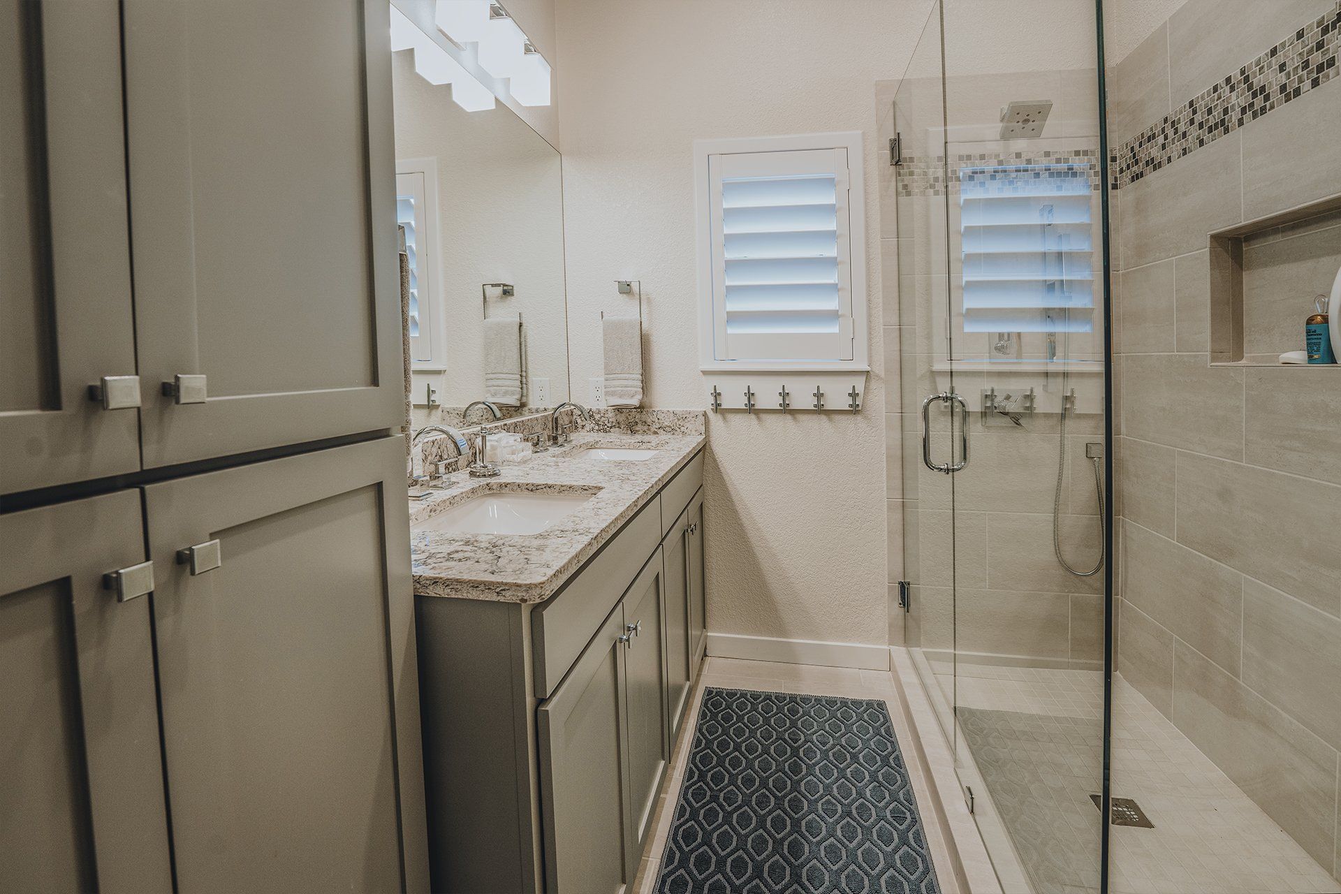A bathroom with two sinks and a walk in shower.