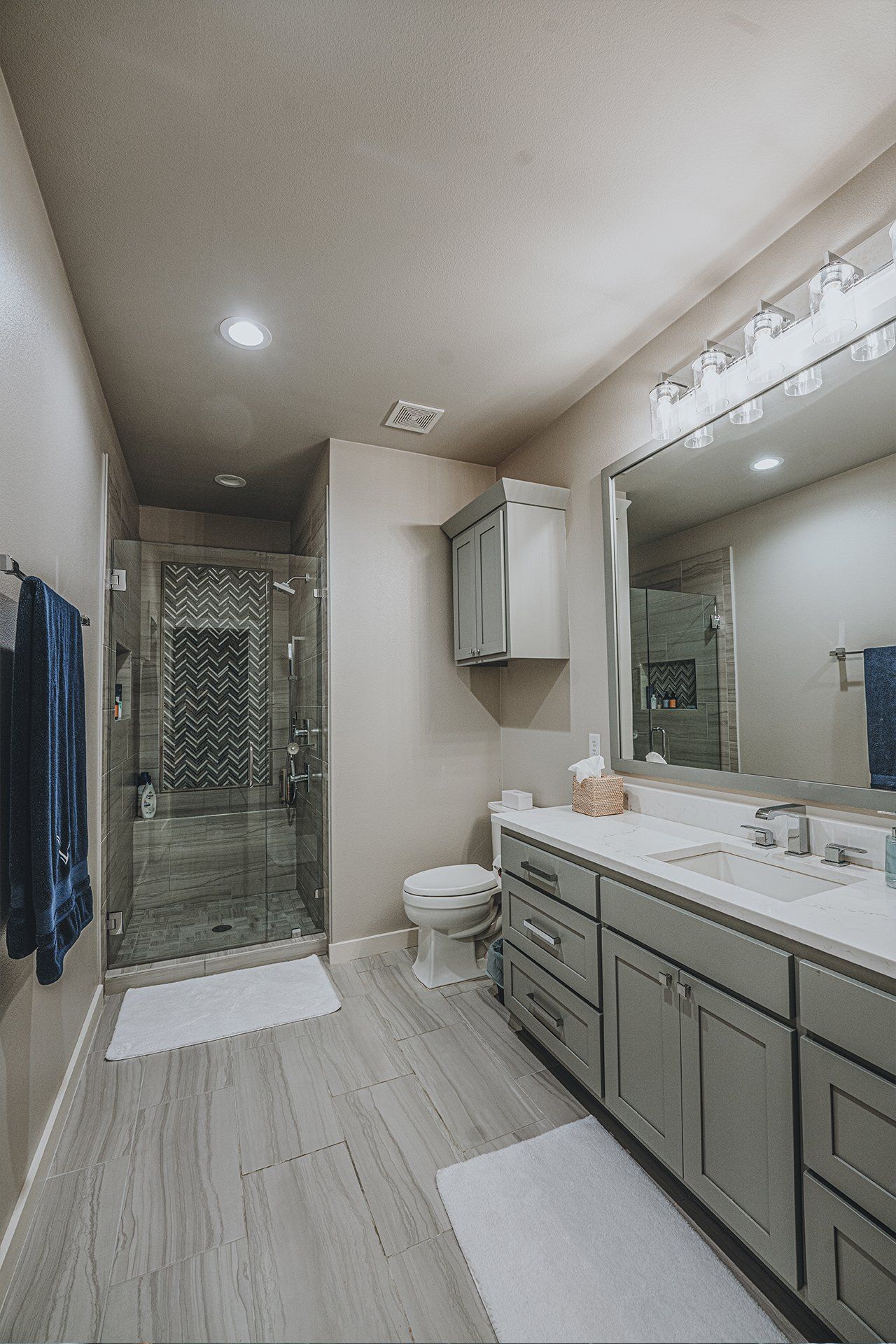 A bathroom with a toilet , sink , mirror and walk in shower.
