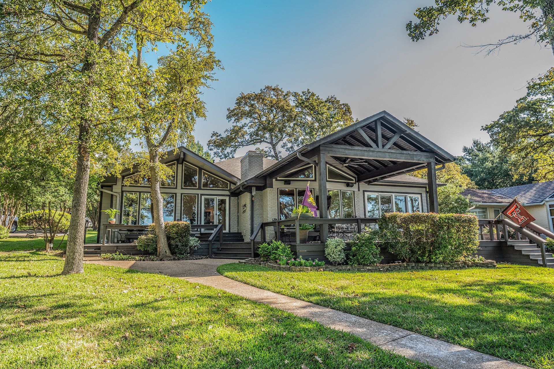 A large house with a large lawn in front of it is surrounded by trees.