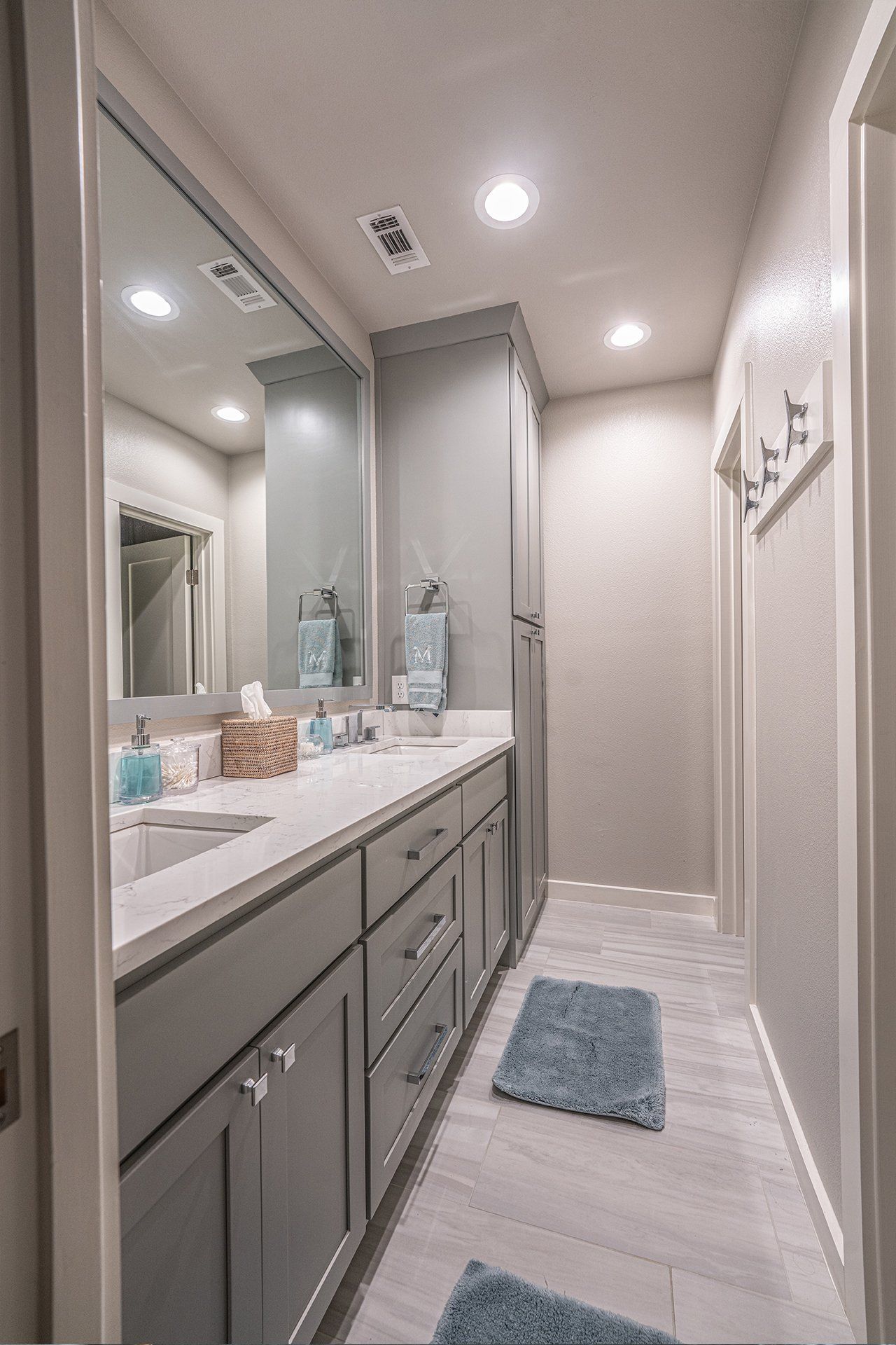 A bathroom with two sinks , a mirror and a rug.