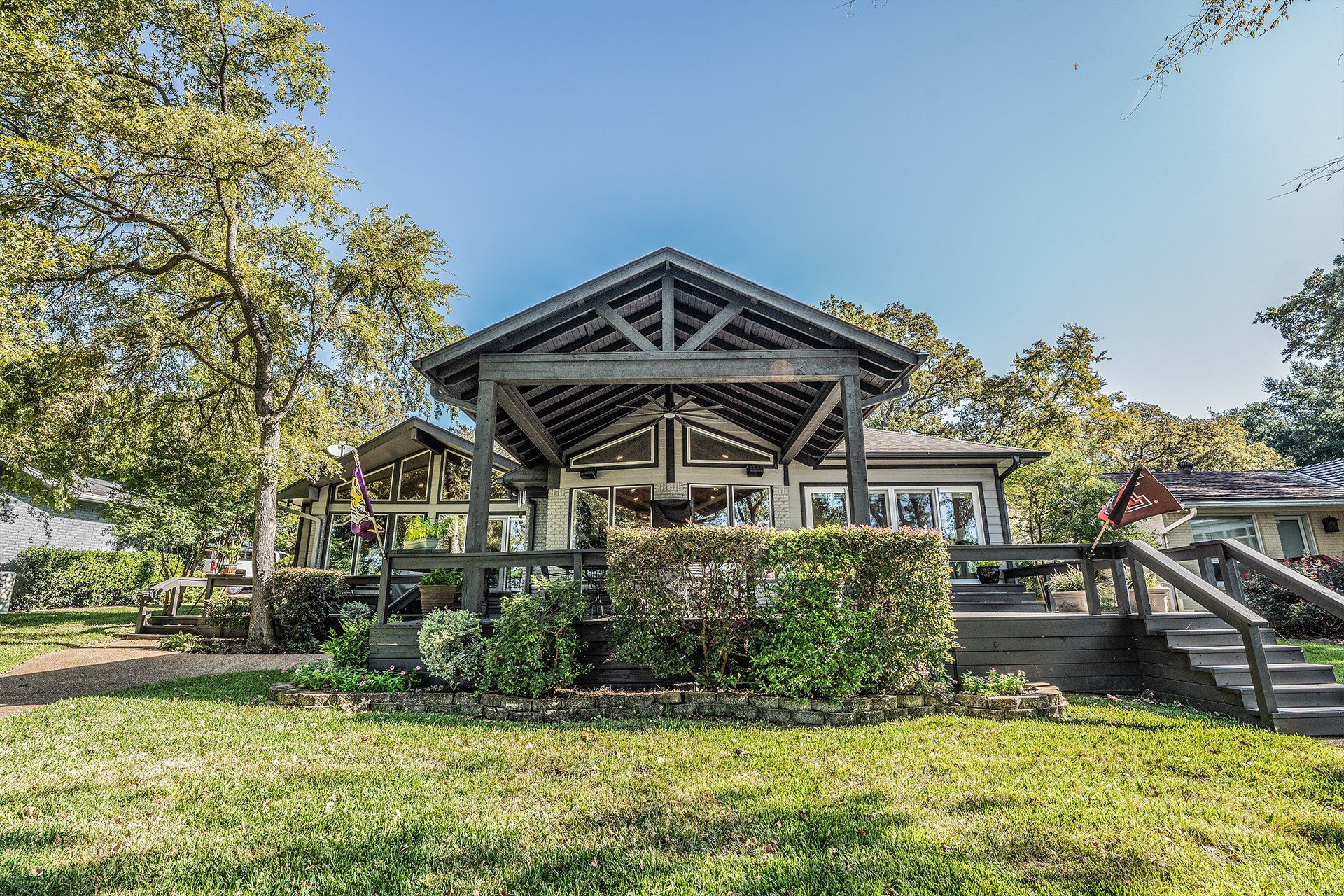 A house with a covered porch and a large lawn in front of it.