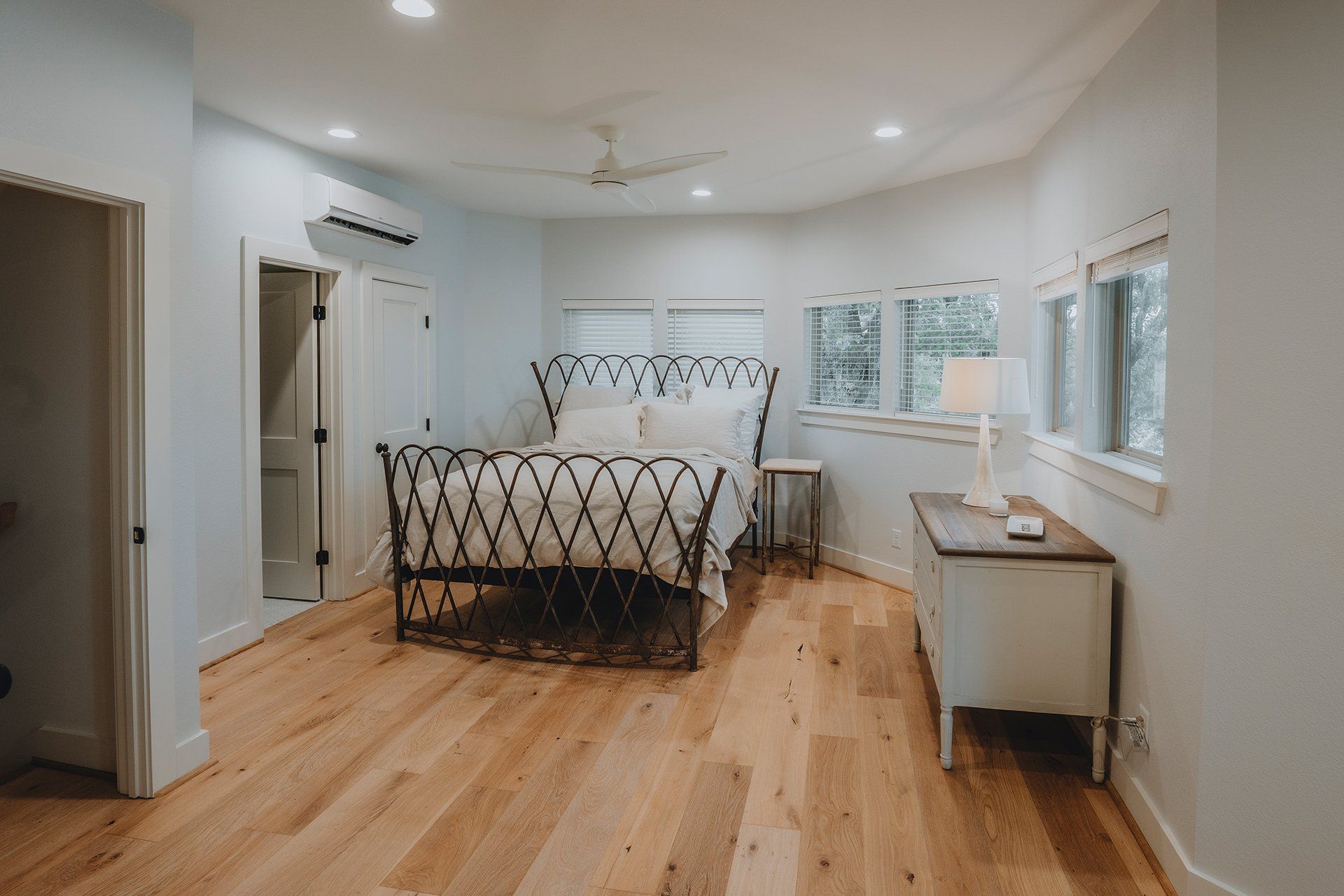 A bedroom with a bed , dresser , and two windows.