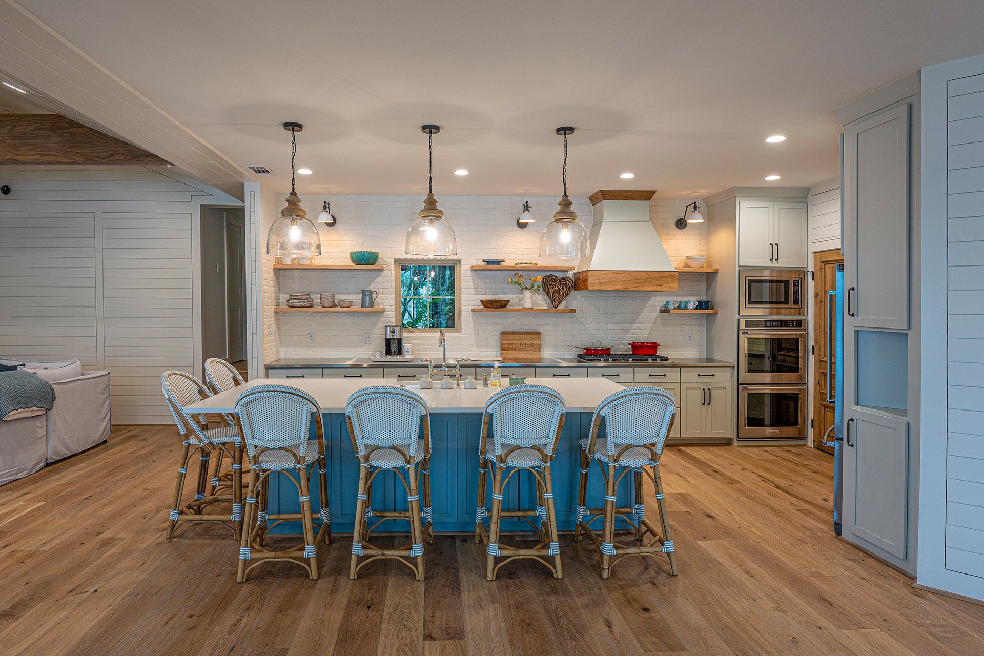 A kitchen with a blue island , white cabinets , and wooden floors.
