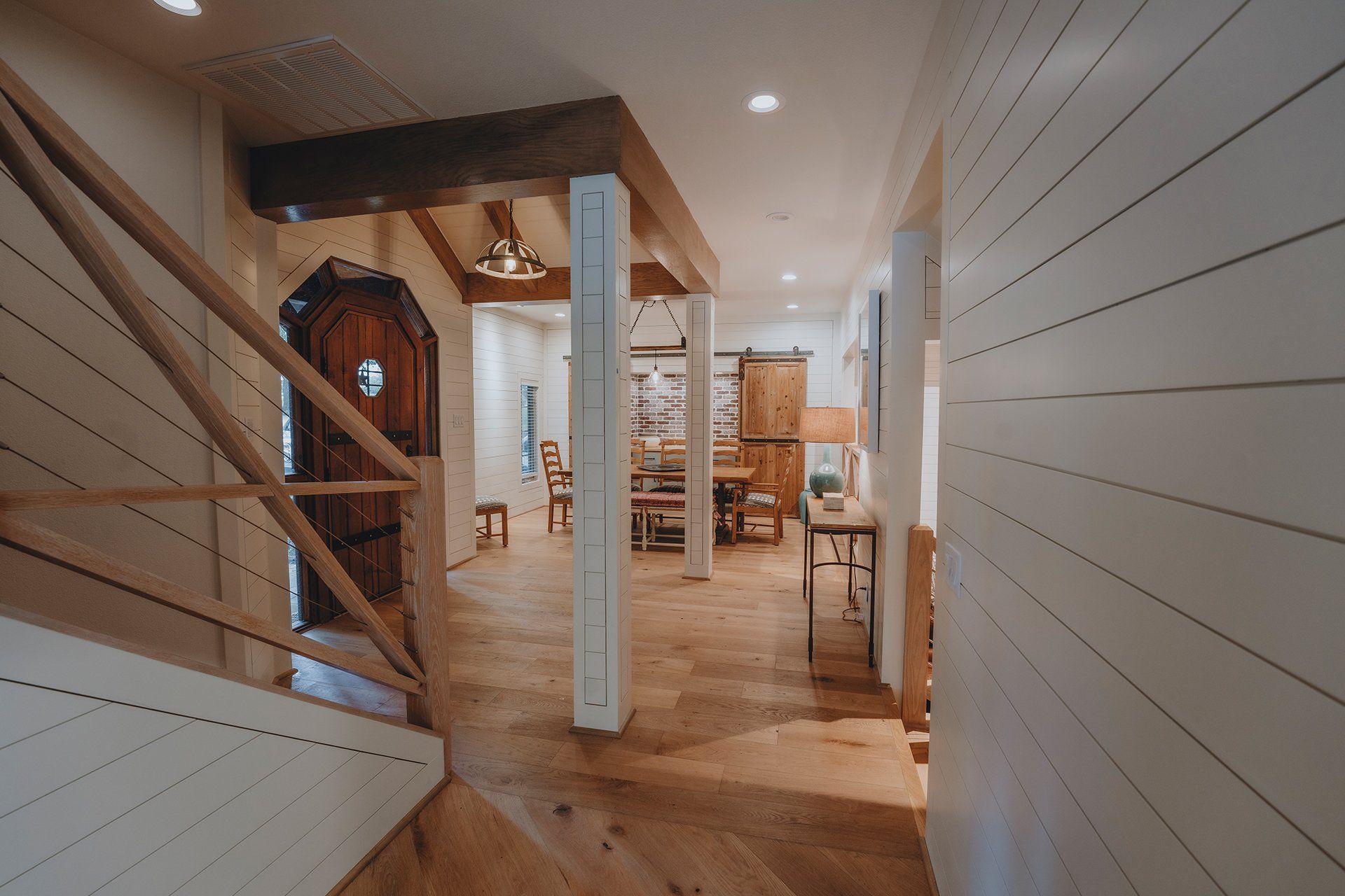 A hallway in a house with a wooden staircase and a wooden door.