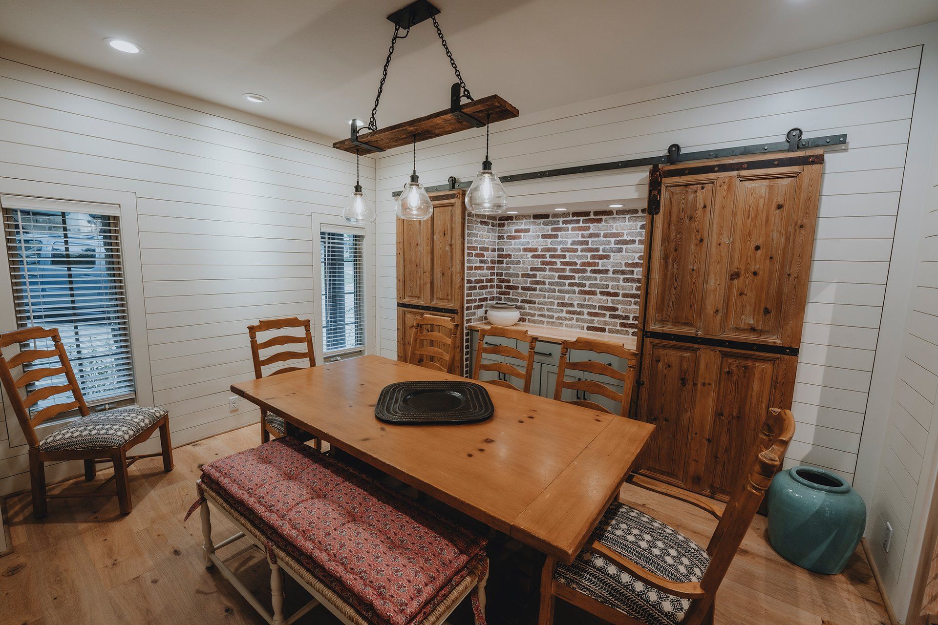 A dining room with a wooden table and chairs and a sliding barn door.