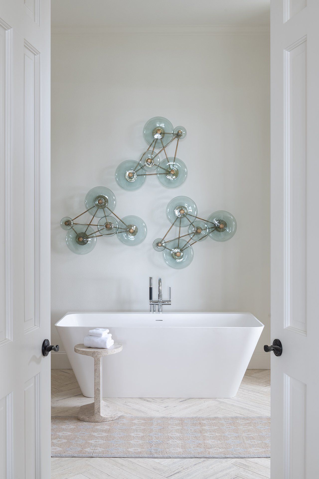 A bathroom with a bathtub and three lights on the wall.