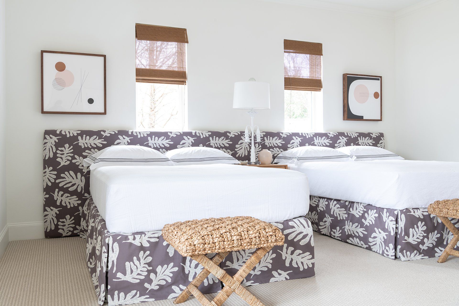 A bedroom with two beds and two wicker benches.