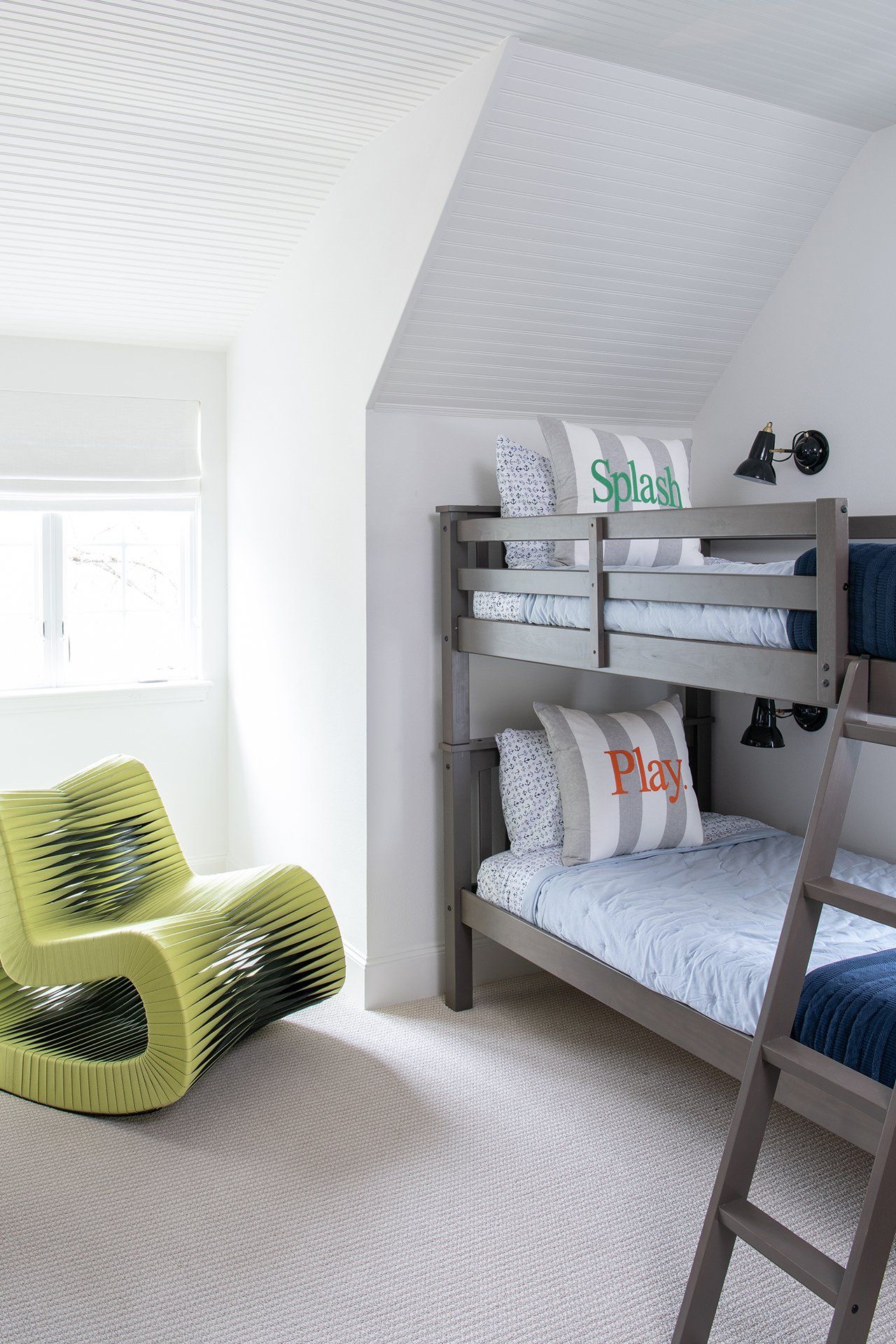 A bedroom with two bunk beds and a chair.