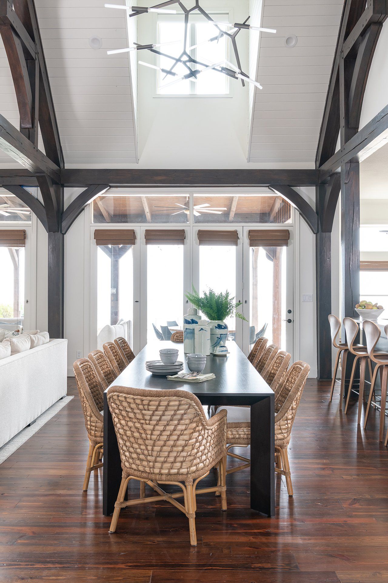 A dining room with a long table and wicker chairs.