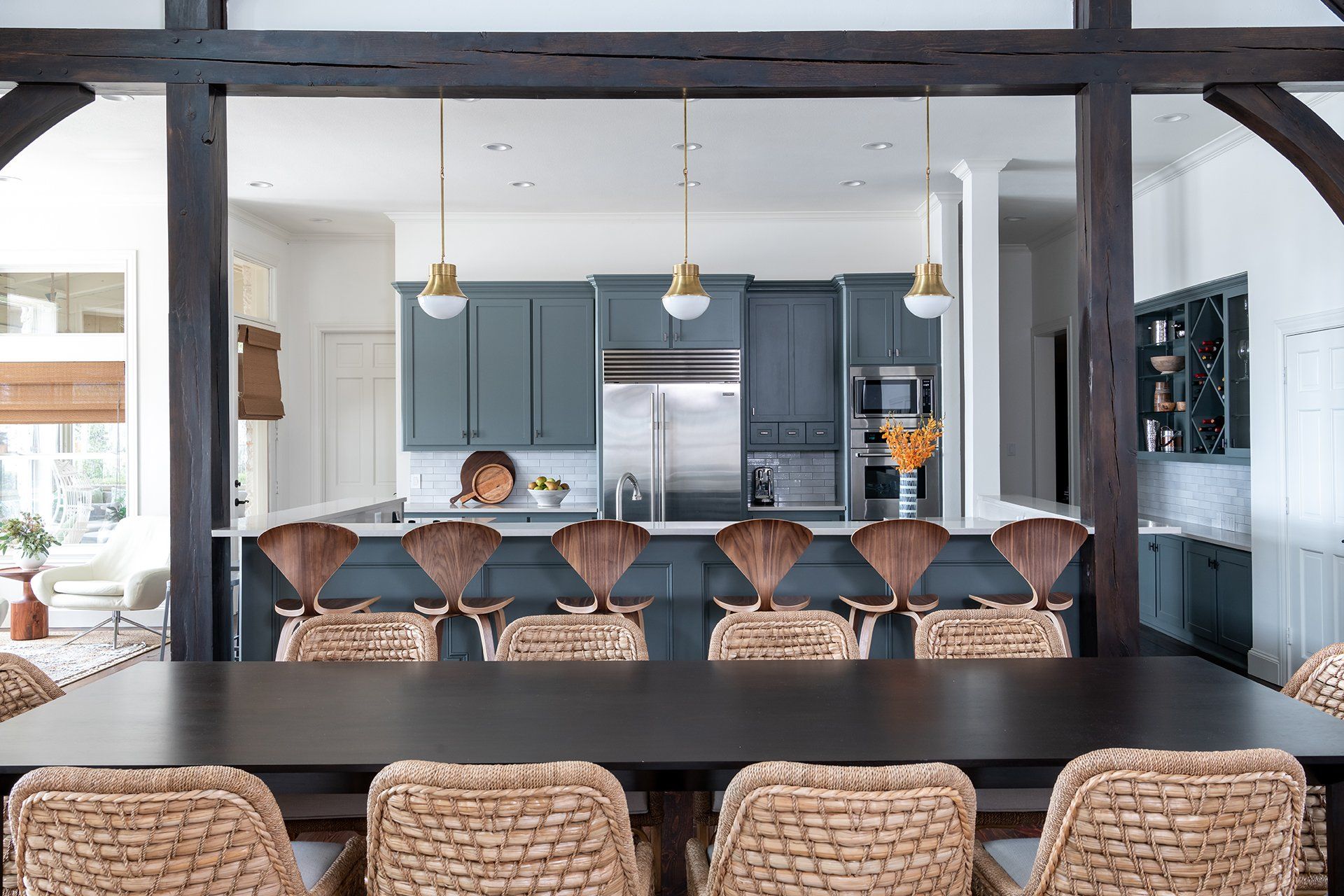 A dining room table with wicker chairs and a kitchen in the background.